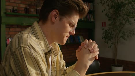 young man praying in a cafe