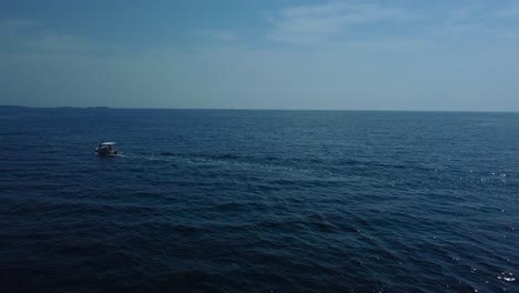 Flying-close-above-a-vacation-yacht-ship-boat-in-a-blue-clear-water-seaside-bay-in-the-idyllic-Adriatic-mediterranean-sea-ocean-by-the-Croatian-coast-with-blue-sky