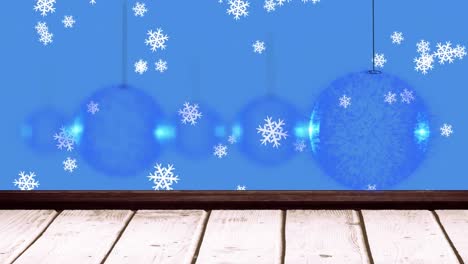 Animation-of-christmas-baubles-dangling-over-wooden-boards-and-snow-falling