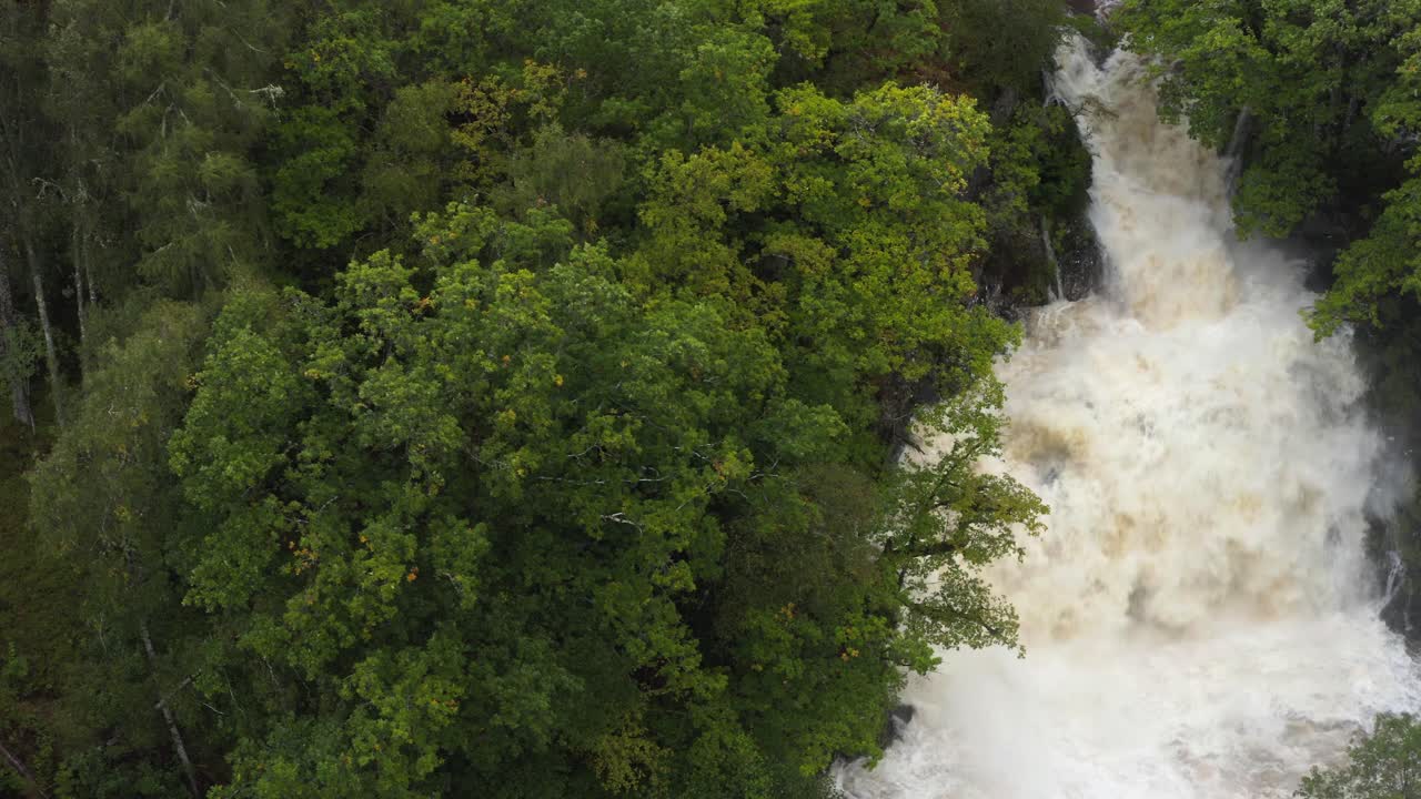 rastreo de izquierda a derecha toma de avión no tripulado de la cascada de eas chia-aig en las tierras altas escocesas en inundación