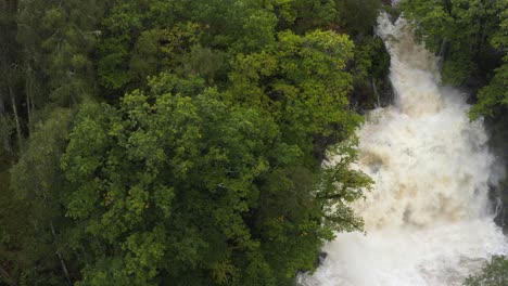 tracking left to right drone shot of eas chia-aig waterfall in scottish highlands in spate