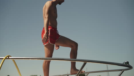 Young-man-diving-off-front-of-yacht-into-water-on-summer-day
