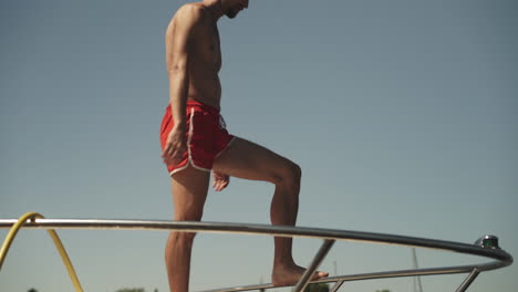 young man diving off front of yacht into water on summer day