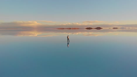Aerial-of-a-lone-figure-walking-along-the-mirrored-reflection-of-the-world's-largest-salt-flat-in-Uyuni-Salt-Flats-,-Bolivia