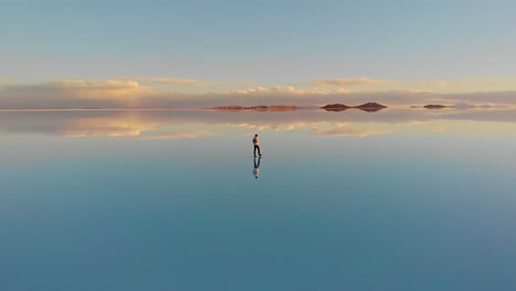 Antena-De-Una-Figura-Solitaria-Caminando-A-Lo-Largo-Del-Reflejo-Reflejado-Del-Salar-Más-Grande-Del-Mundo-En-El-Salar-De-Uyuni,-Bolivia