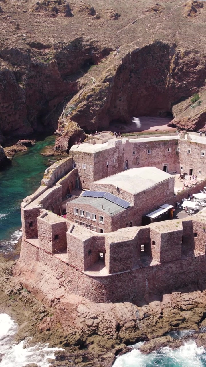 Orbita aerea verticale a bassa angolazione del Forte delle Berlengas sopra l'acqua turchese dell'Atlantico in Portogallo.