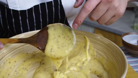 el chef señala la calidad de la salsa de ensalada césar en su cuchara de madera para mezclar