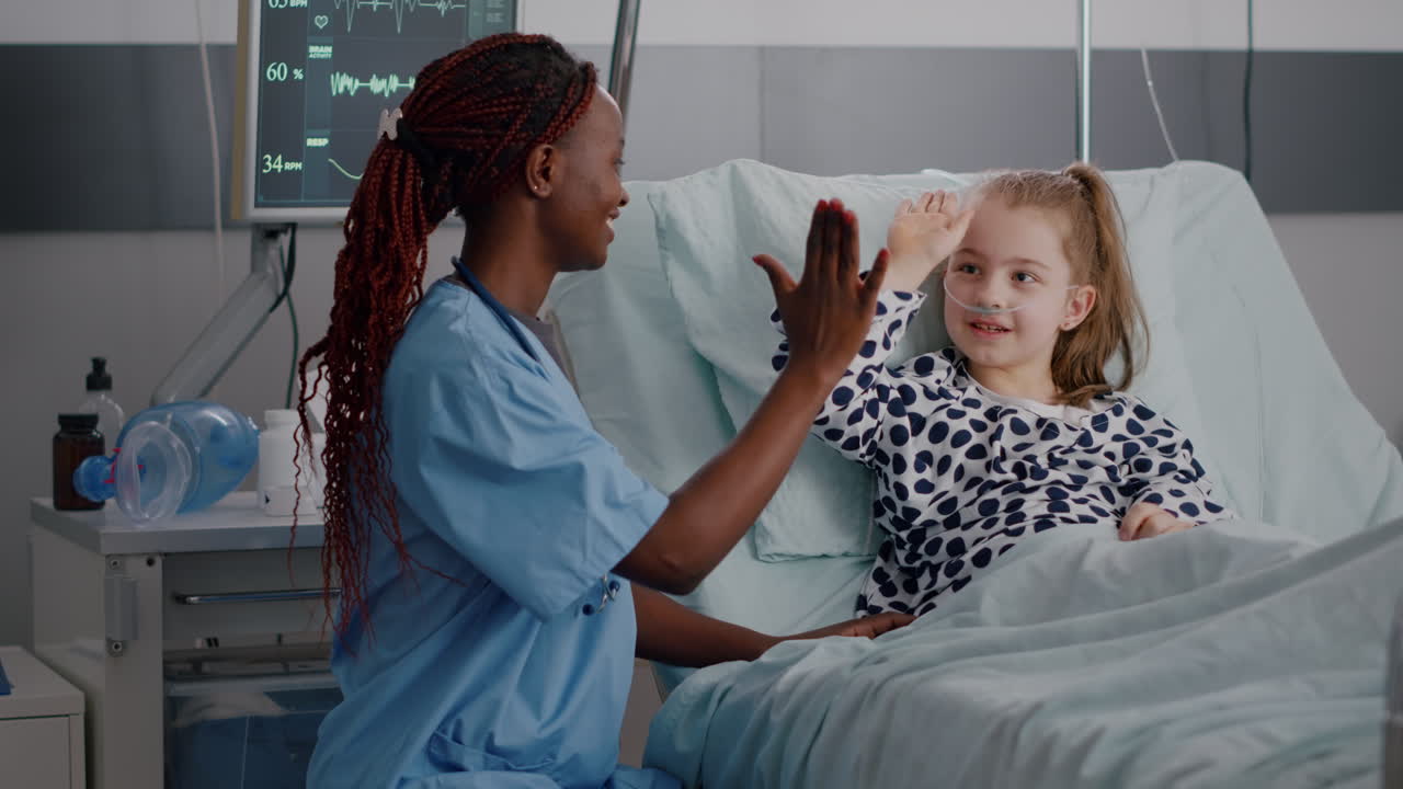 African american pediatrician nurse sitting beside sick child giving high five