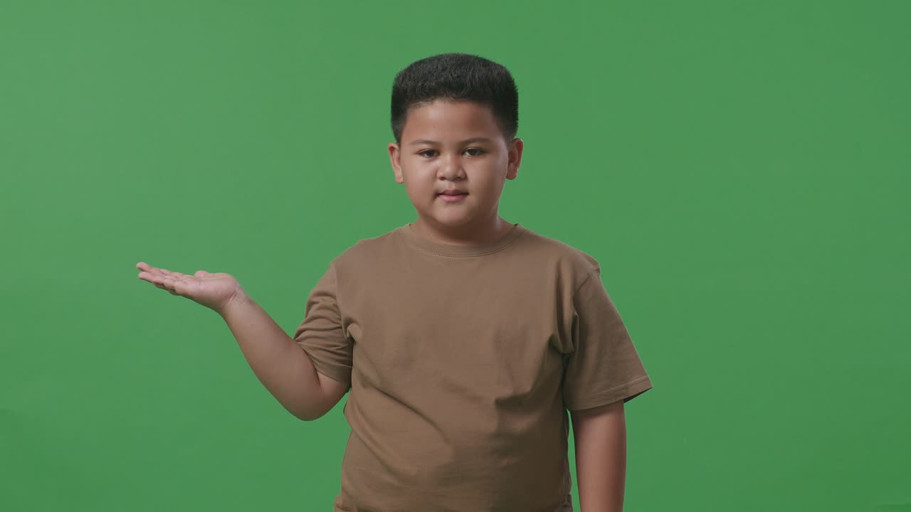 녹색 스크린에 서 있는 동안 을 가리키는 미소로 아시아 소년