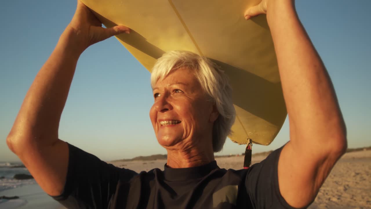 Senior woman with a surfboard smiling