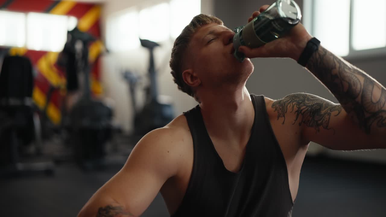 hombre bebiendo agua después de un entrenamiento en el gimnasio