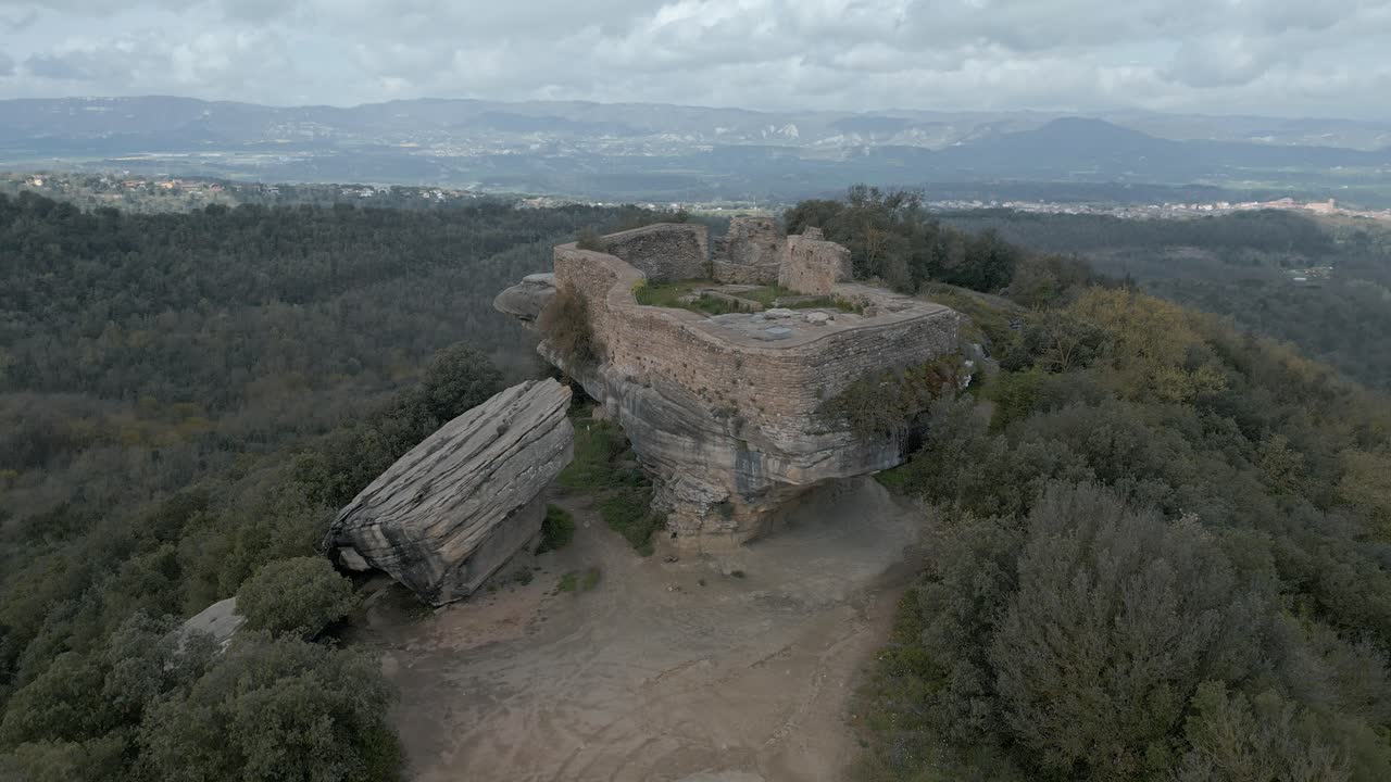 Majestic ruins of taradell castle stand atop a rocky outcrop, surrounded by lush green forests, overlooking the picturesque plains of catalonia