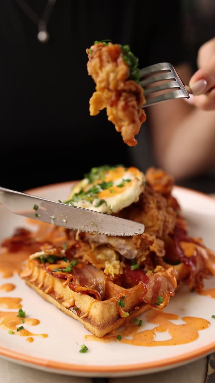 Primo piano di una persona che taglia e mangia pollo fritto e waffle
