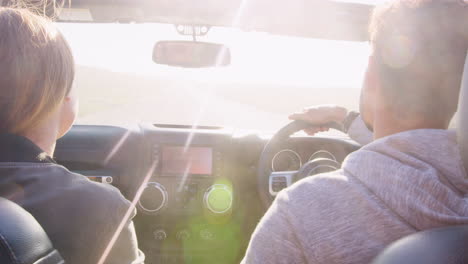 Young-couple-driving-with-sunroof-open,-rear-passenger-POV