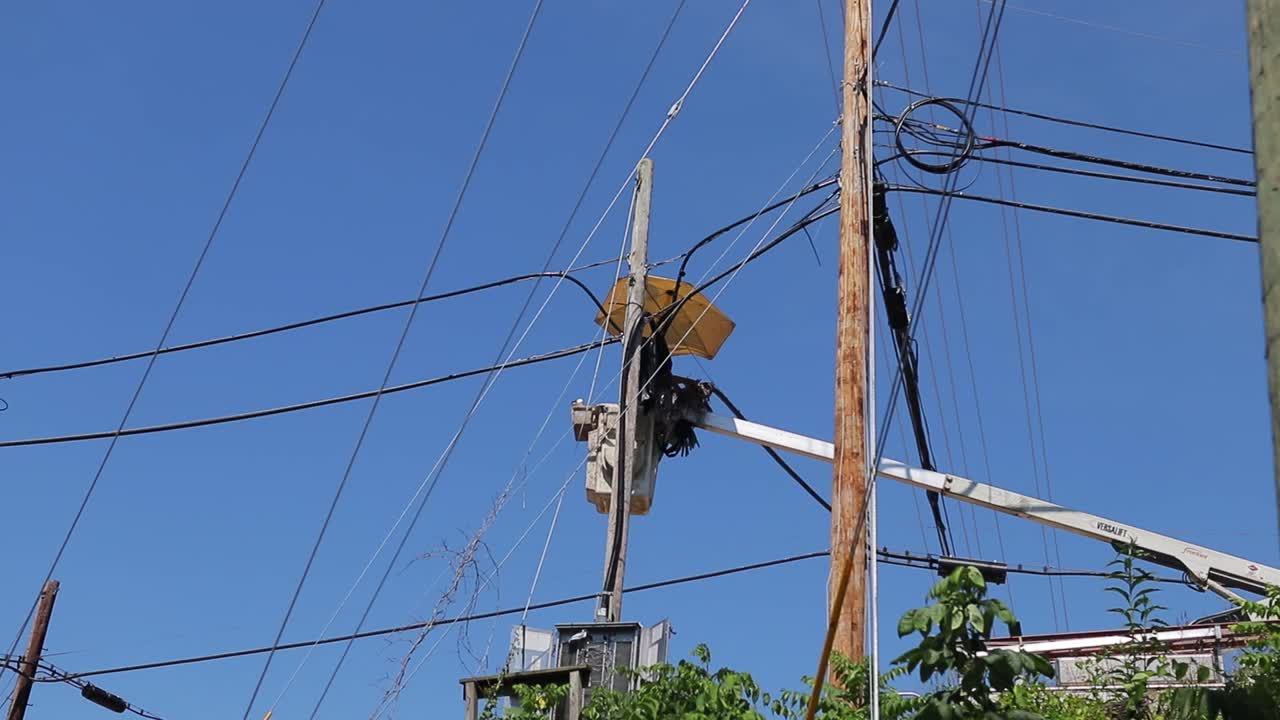 Workman Repairing Telecommunications Cables From Bucket Of Boom Truck Under Umbrella