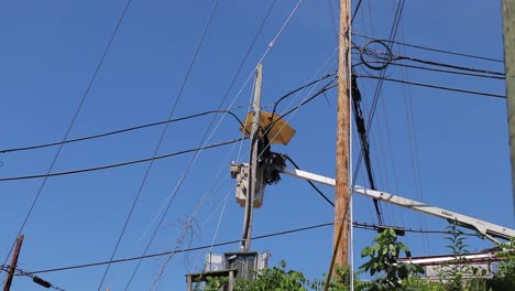 workman repairing telecommunications cables from bucket of boom truck under umbrella