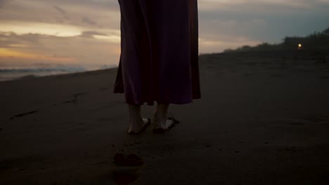 girl barefooted on the sandy seashore during sunset