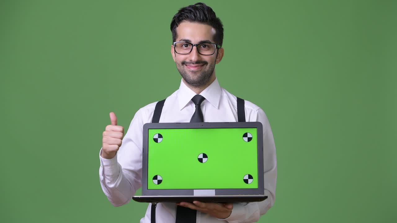 joven empresario persa barbudo y guapo contra un fondo verde