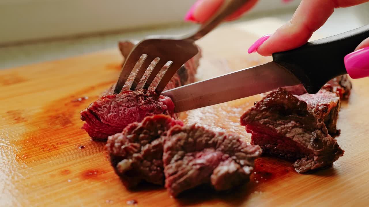 Slow Motion Scene of Knife Cutting Through Juicy Red Meat on Wooden Board