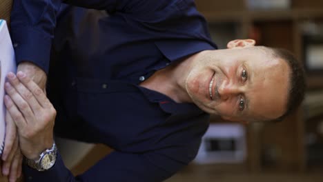 and-adult-man-with-stubble-in-a-black-shirt-sits-in-a-cafe-smiling-and-posing-for-the-camera