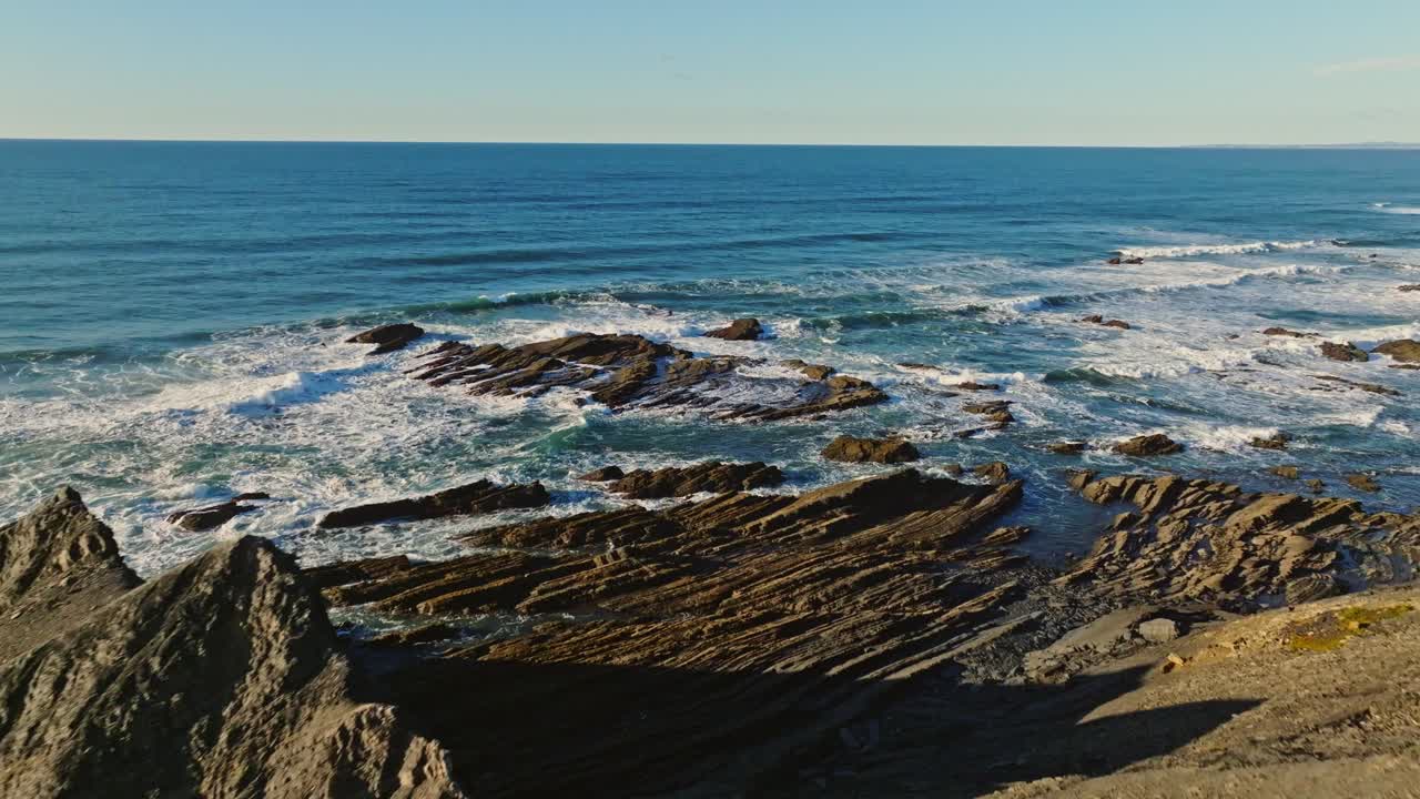 Drone flying fast past a V shape rock revealing a beautiful vast opean Atlantic Ocean