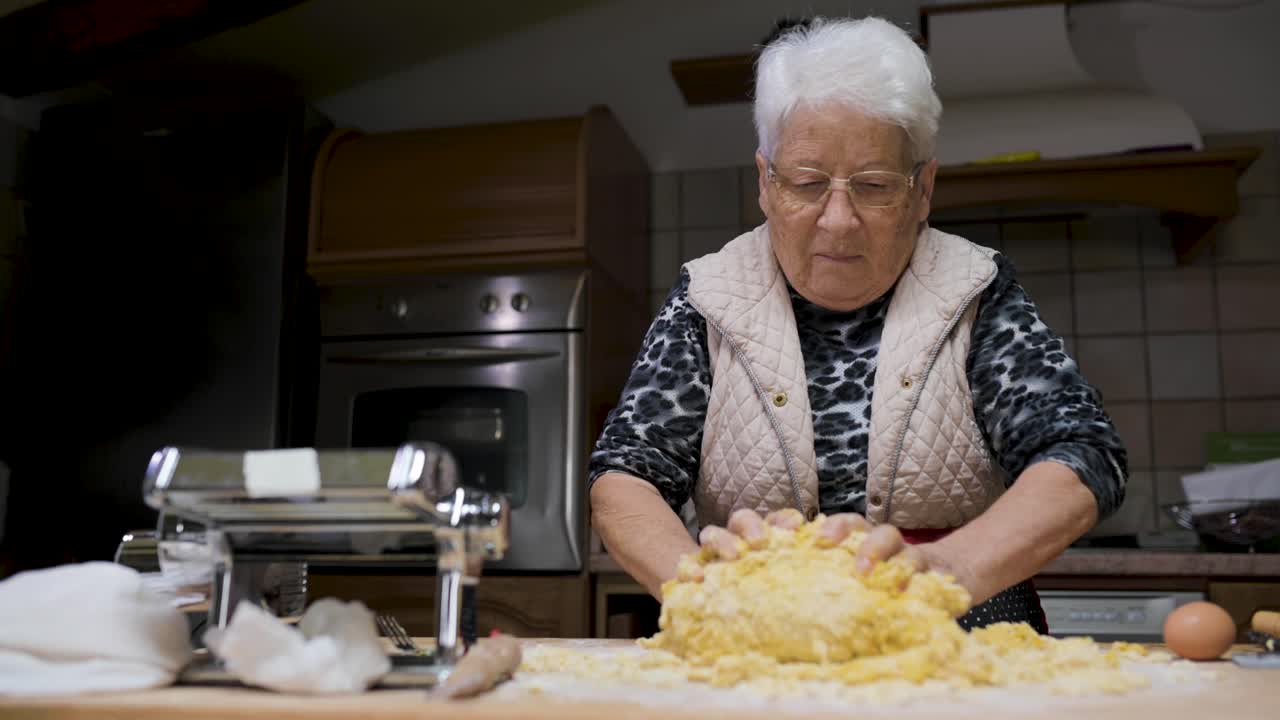 mujer de edad amasar la masa en la cocina