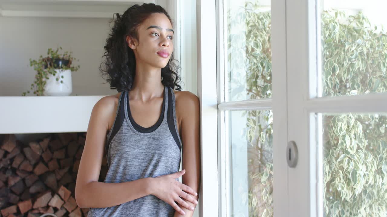 African American woman leaning by door adjusting pose while camera pulling back for shoot smiling