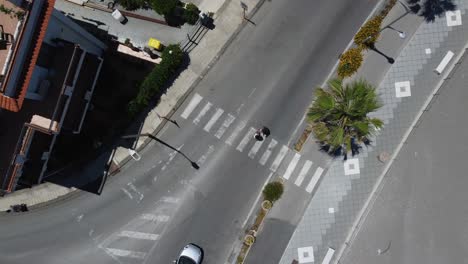 bird's-eye view of a couple walking across a crosswalk with cars on the road