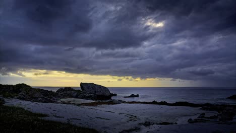 dramatic arctic coastal landscape with dramatic clouds. time lapse. rocky shore, sandy beach covered with seaweed in bright summer night. lofoten islands, northern norway.