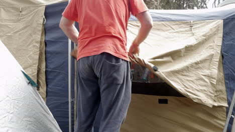 Man-rolling-up-canvas-tent-windows-in-the-morning