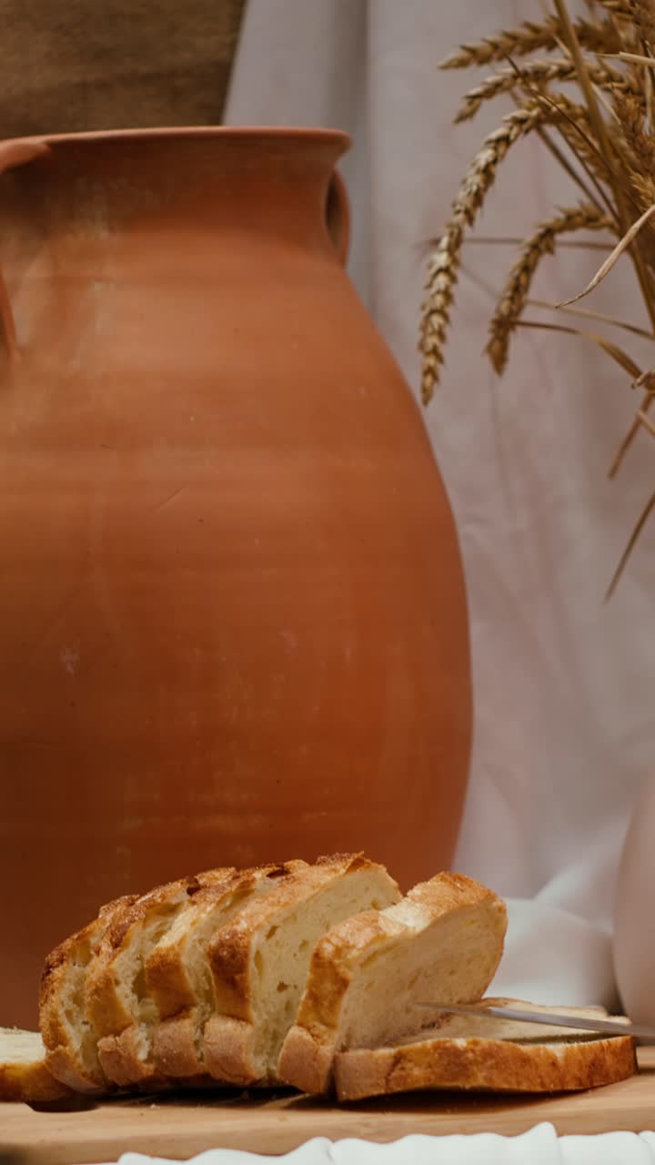 Sliced Bread on Cutting Board with Terracotta Pot and Wheat Stalks