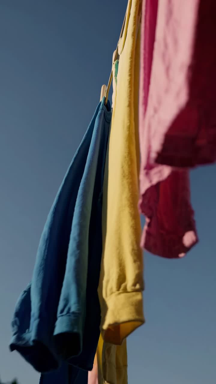 Ropa colorida secándose en un tendedero contra un cielo azul.