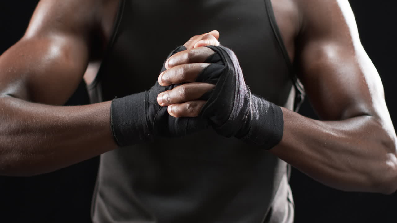 boxeador afroamericano envuelve sus manos para boxear en un fondo negro