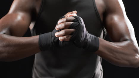 african american boxer wraps his hands for boxing on a black background