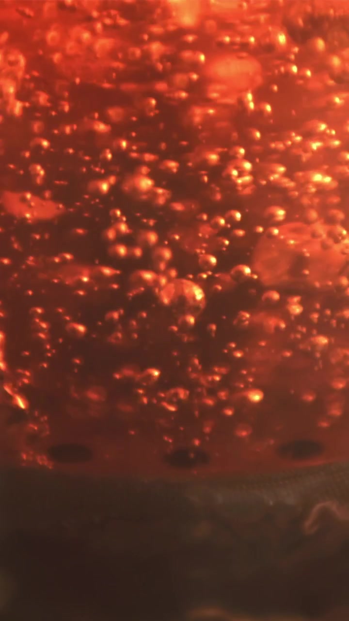 Bolle arancioni vivaci che salgono e scoppiano in un liquido