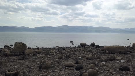 Strange-creepy-Martian-mountain-range-rocky-alien-stone-beach-coastline-fast-forward-over-ocean