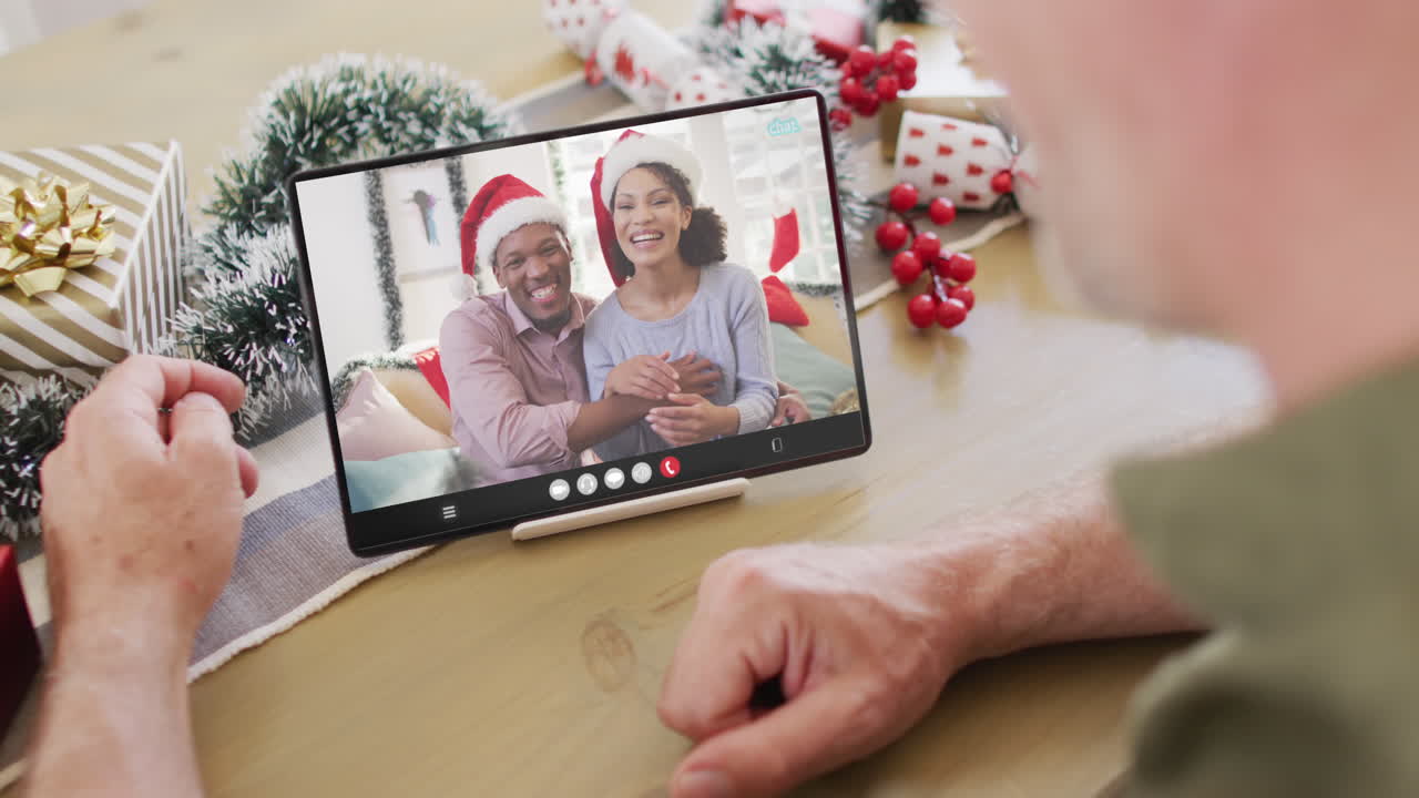 hombre caucásico con decoraciones de navidad teniendo llamada de video de tableta con una feliz pareja diversa