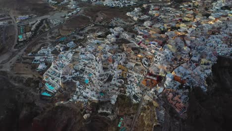 Nachts-In-Oia-Mit-Weißen-Höhlenhäusern-Und-Villenansicht-Von-Der-Drohne-Während-Des-Sonnenuntergangs-In-Santorini,-Griechenland