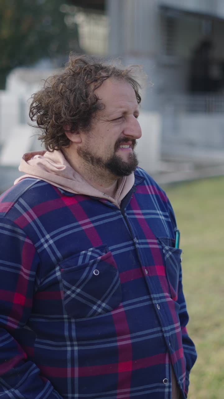 Man with curly hair and beard wearing a plaid shirt