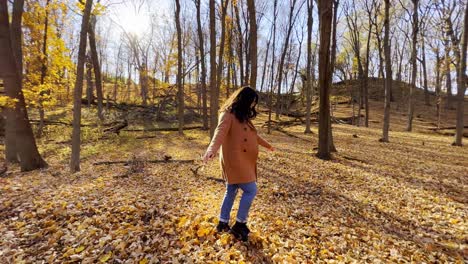 niña caminando en un bosque durante el otoño en minnesota con hojas amarillas cayendo