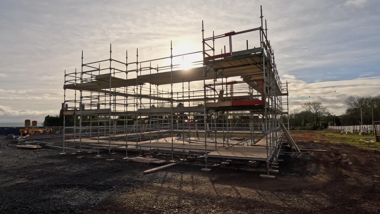Three story scaffold platform set up in grassy, sunny field, copy space