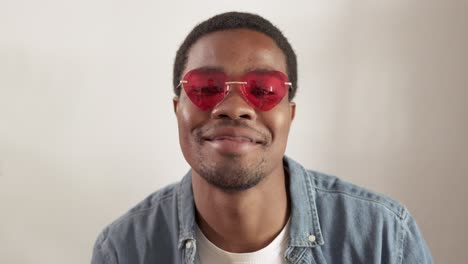 young black man wearing red heart-shaped sunglasses smiling