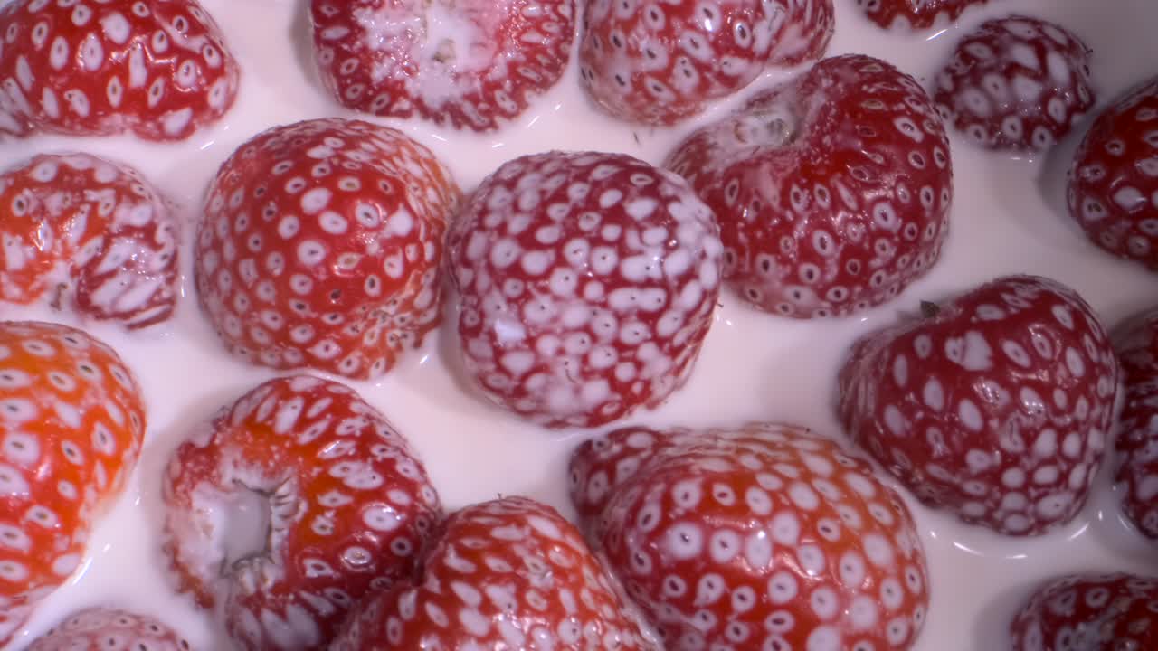 Rotate of ripe strawberries covered with layer of cream. Camera rotation 360 degrees, close-up.