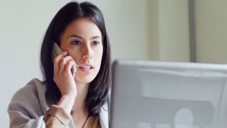 mujer hablando por móvil mientras usa una computadora portátil 4k