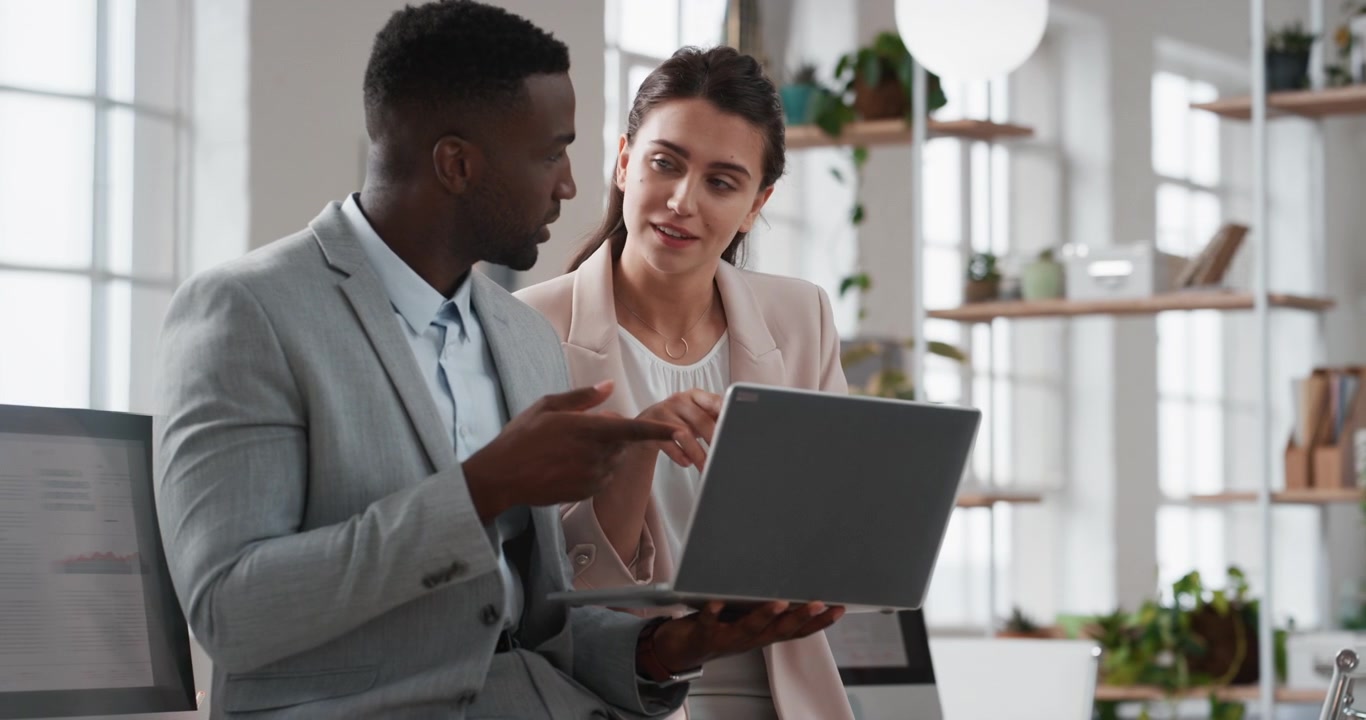 Colleghi che discutono di un progetto su un laptop in un ufficio moderno