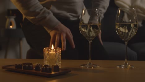 hombre planeando una velada romántica en casa en el salón con vino y chocolates 1