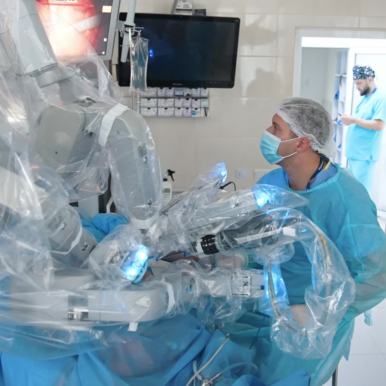 Surgeon at medical robot in the operating room. Modern medical equipment in clinic. Minimally invasive surgery with robotic machine. Robotic surgery