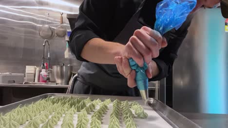 young chef making large tray with green meringues