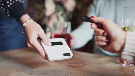 close up of customer paying in hotel restaurant using contactless card reader