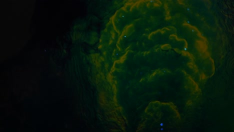 una entidad verde oscura y melancólica pulsa junto con diminutos orbes azules